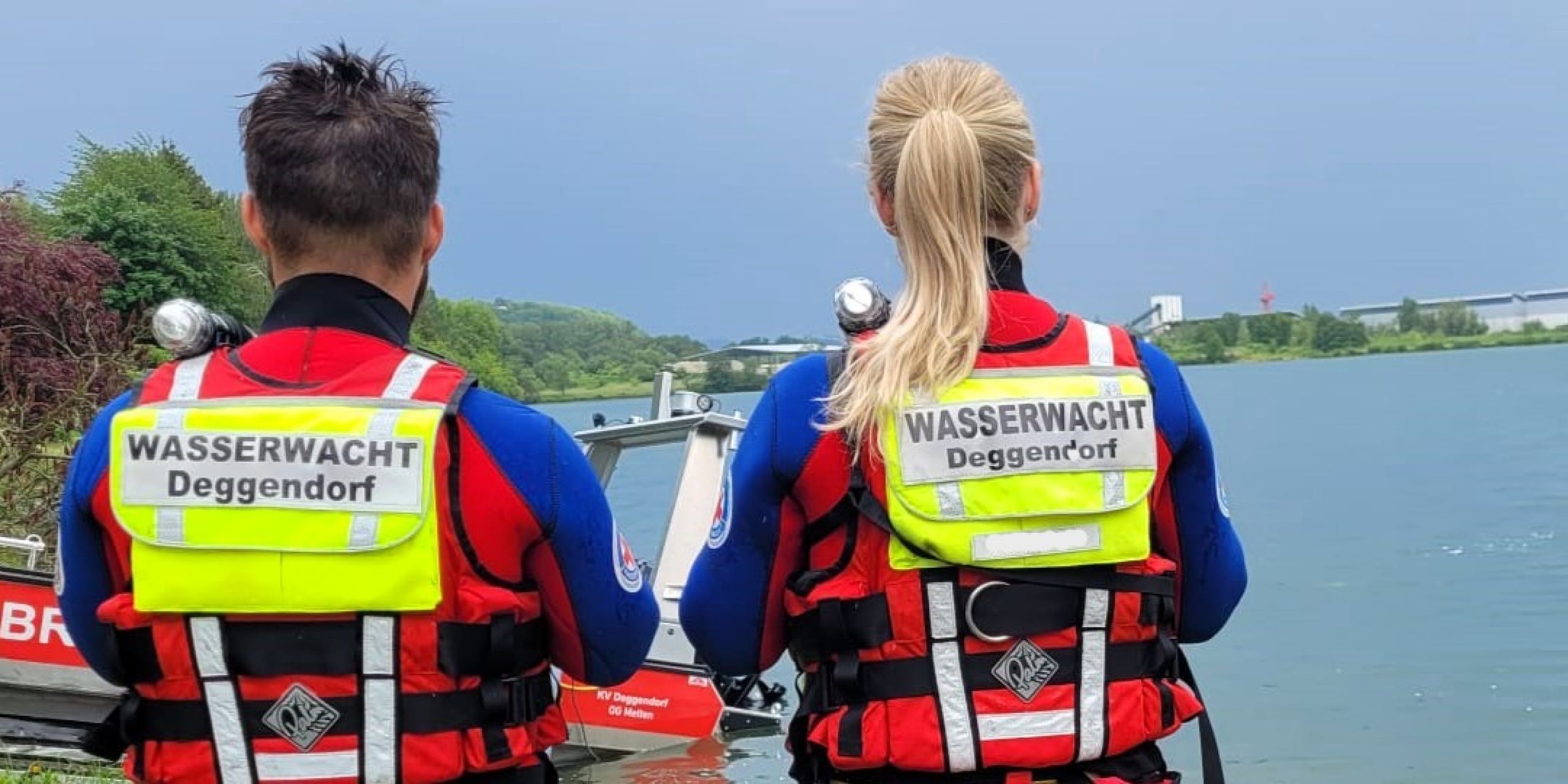 Zwei Wasserretter mit dem Rücken zur Kamera mit Blick auf die Donau