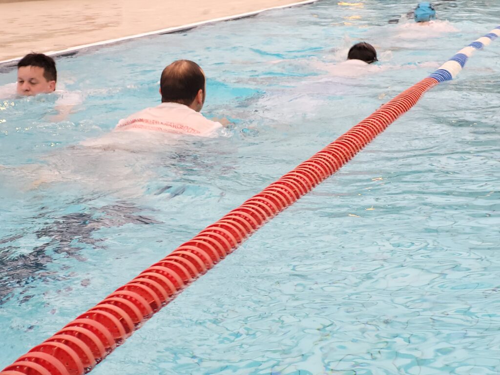 Schwimmbecken mit Schwimmern in Kleidung
