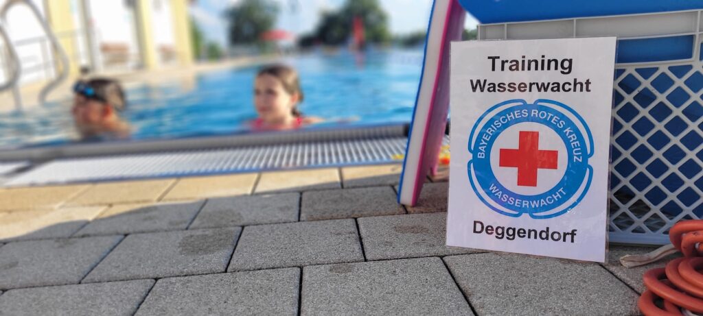 Blick auf das Becken im Freibad mit Trainingsausrüstung im Vordergrund.